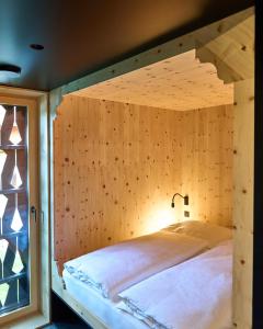 Bett in einem Zimmer mit einer Holzwand in der Unterkunft KOKON Apartments in Leutasch