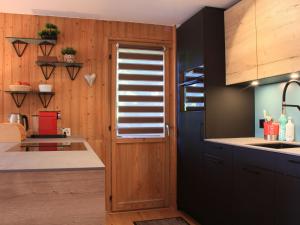 a kitchen with wooden walls and a door with a window at Apartment Goeland n-4 by Interhome in Villars-sur-Ollon