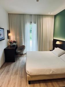 um quarto com uma cama, uma secretária e uma janela em Hotel Capolago em Varese