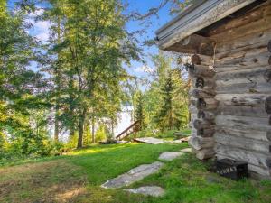 a log cabin in the woods next to a yard at Holiday Home Kelosyväri 17 by Interhome in Nilsiä
