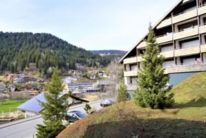 a building with a grassy hill next to a street at Lovely 1-bedroom vacation studio apartment with pool and sauna in Laax