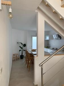 a kitchen and dining room with white walls and a staircase at AmuraHouse. Private terrace BBQ. Centric and cosy. in Cotillo