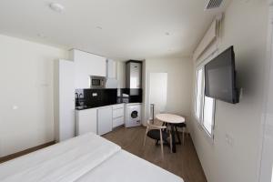 um quarto branco com uma cama e uma pequena mesa em Apartamentos Centro Jardines em Madri