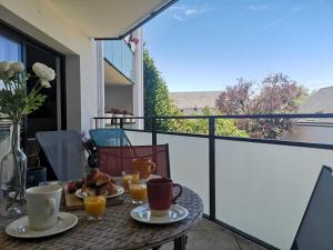 een tafel met kopjes en borden eten op een balkon bij Apartment Stella Marine-2 by Interhome in Carnac