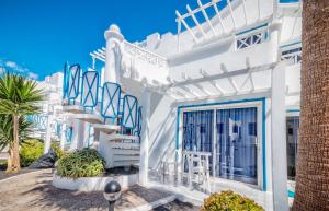 a white house with blue stairs and a palm tree at Apartamentos LIVVO Oasis in Puerto del Carmen