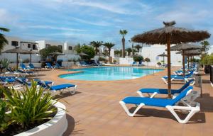 una piscina con sillas y sombrillas junto a un complejo en Apartamentos LIVVO Oasis, en Puerto del Carmen