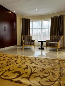 Habitación con 2 sillas, mesa y alfombra. en Open House Hotel en Mbabane