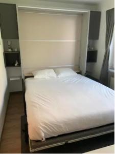 ein Bett mit weißer Bettwäsche und Kissen in einem Schlafzimmer in der Unterkunft Lovely 1-bedroom vacation studio apartment with pool and sauna in Laax