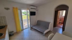 sala de estar con silla y puerta corredera de cristal en Apartments Miki, en Pag