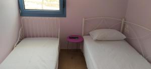 two twin beds in a small room with a window at Theros house in Kythira
