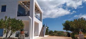 a white house with a balcony and trees at Theros house in Kythira
