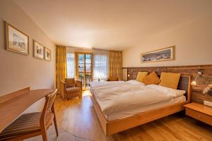 a bedroom with a large bed and a desk at Hotel Pollux in Zermatt