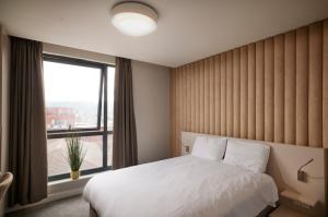 a bedroom with a bed and a large window at LUSSO Macclesfield Serviced Apartments in Macclesfield