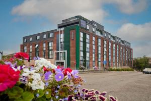 a building with a bunch of flowers in front of it at LUSSO Macclesfield Serviced Apartments in Macclesfield
