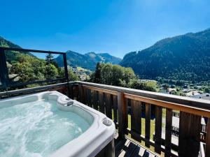 a hot tub on a balcony with a view of mountains at L'O Rouge - Apt A202 - BO Immobilier - Châtel -remises sur les forfaits de skis Châtel ou Portes du soleil in Châtel
