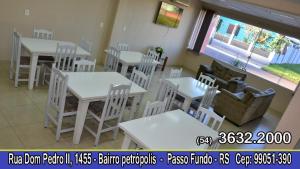 een eetkamer met witte tafels en witte stoelen bij Hotel Traveling in Passo Fundo