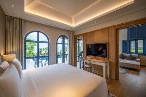 ein Schlafzimmer mit einem großen weißen Bett und einem Balkon in der Unterkunft Centara Mirage Resort Mui Ne in Mui Ne