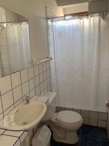 a bathroom with a white toilet and a sink at Hostal El Amigo in Paracas