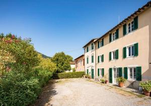 eine unbefestigte Straße neben einem Gebäude mit grünen Rollläden in der Unterkunft La Dimora di Corte in Lucca