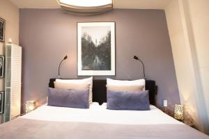 1 dormitorio con 1 cama grande con almohadas azules en Zwanestein Canal House, en Ámsterdam