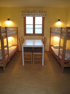 a room with a table and two bunk beds at Badholmens Vandrarhem in Fjällbacka