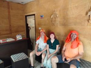 Trzy kobiety z pomarańczowymi włosami siedzące w pokoju w obiekcie Jaisalmer Tofu safari w mieście Jaisalmer