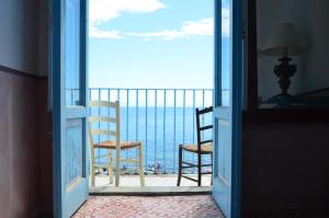 an open door to a balcony with two chairs and the ocean at La Sirena in Filicudi