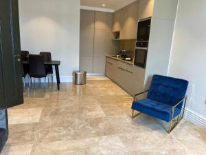 a living room with a blue chair and a kitchen at Bright & Modern 2 bedroom In Hendon in Hendon