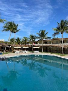 a large swimming pool with palm trees and umbrellas at Arena Carneiros Hotel by AFT in Tamandaré