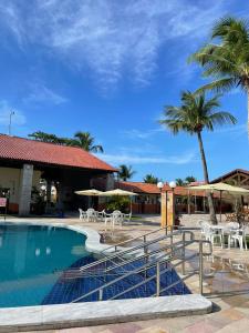 a pool with chairs and umbrellas and palm trees at Arena Carneiros Hotel by AFT in Tamandaré