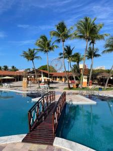 a bridge over a swimming pool with palm trees at Arena Carneiros Hotel by AFT in Tamandaré