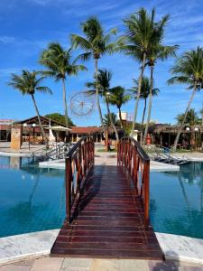 a wooden bridge over a pool with palm trees at Arena Carneiros Hotel by AFT in Tamandaré