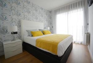sypialnia z łóżkiem z żółtymi poduszkami i żółtym kocem w obiekcie GALIHOST - Apartamento con piscina en Canelas, Sanxenxo w mieście Sanxenxo