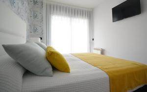 sypialnia z łóżkiem z żółtym kocem i oknem w obiekcie GALIHOST - Apartamento con piscina en Canelas, Sanxenxo w mieście Sanxenxo