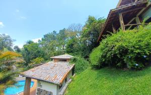 a house with a rusty roof next to a swimming pool at Chalé Serra Cantareira in Mairiporã