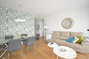 salon z kanapą, stołem i krzesłami w obiekcie GALIHOST - Apartamento con piscina en Canelas, Sanxenxo w mieście Sanxenxo