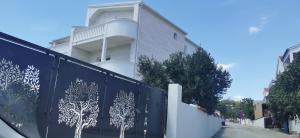 a fence with trees painted on it in front of a building at Zvonćica Deluxe in Vodice