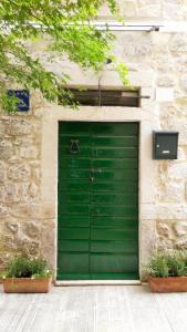 una puerta verde de garaje en un edificio con dos plantas en Rooms Livia, en Trogir