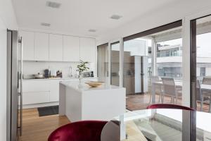kuchnia i salon z białymi szafkami i stołem w obiekcie Modern 3BR with Terrace in Benfica w Lizbonie
