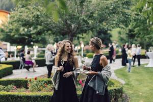 Deux femmes se tenant côte à côte dans un parc dans l'établissement Alpenpalace Luxury Hideaway & Spa Retreat, à Lutago