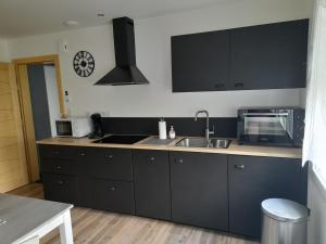 a kitchen with black cabinets and a sink and a microwave at Au fil du bois in Contrexéville