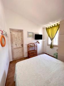 Schlafzimmer mit einem weißen Bett und einem TV in der Unterkunft DOMUS HENRICUS -THREEROOM APARTMENT IN PORTO POLLO 400 Meters from the sea in Porto Pollo