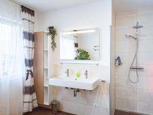 a white bathroom with a sink and a shower at Holiday Home Pusteblume by Interhome in Hessenburg