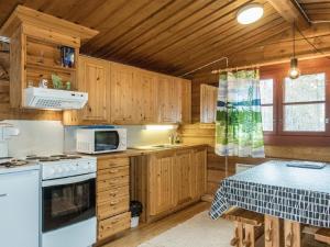 La cuisine est équipée de placards en bois et d'une cuisinière blanche. dans l'établissement Holiday Home Livon pirtti 2 by Interhome, à Posio