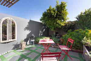 a patio with two red chairs and a table at Blouberg Studio Apartment in Bloubergstrand