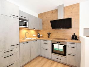 a kitchen with white cabinets and a flat screen tv at Apartment Bernadette by Interhome in Aschau