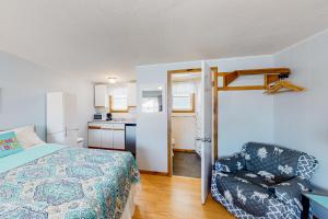 a bedroom with a bed and a chair and a kitchen at Coastal Calm A in Wells