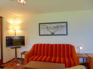 a living room with a red couch and a flat screen tv at Apartment Victoria A-B-C-10 by Interhome in Crans-Montana