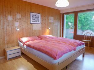 ein Schlafzimmer mit einem großen Bett in einem Zimmer mit Holzwänden in der Unterkunft Apartment Victoria A-B-C-10 by Interhome in Crans-Montana