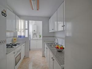 una cocina con armarios blancos y un bol de fruta en la barra en Apartment Pueblo II by Interhome, en Calpe
